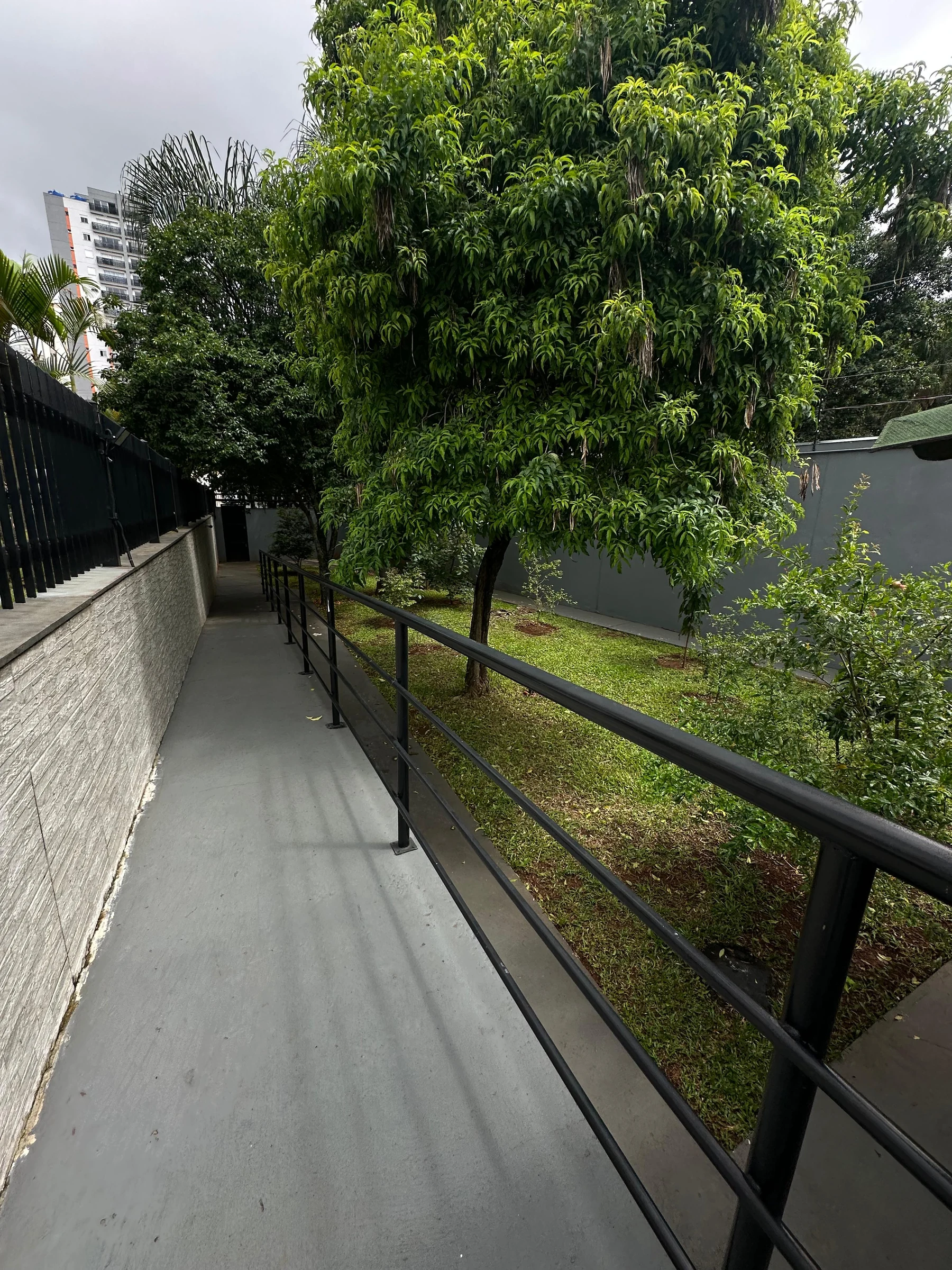 Área externa concluída com circulação, jardim e guarda-corpo