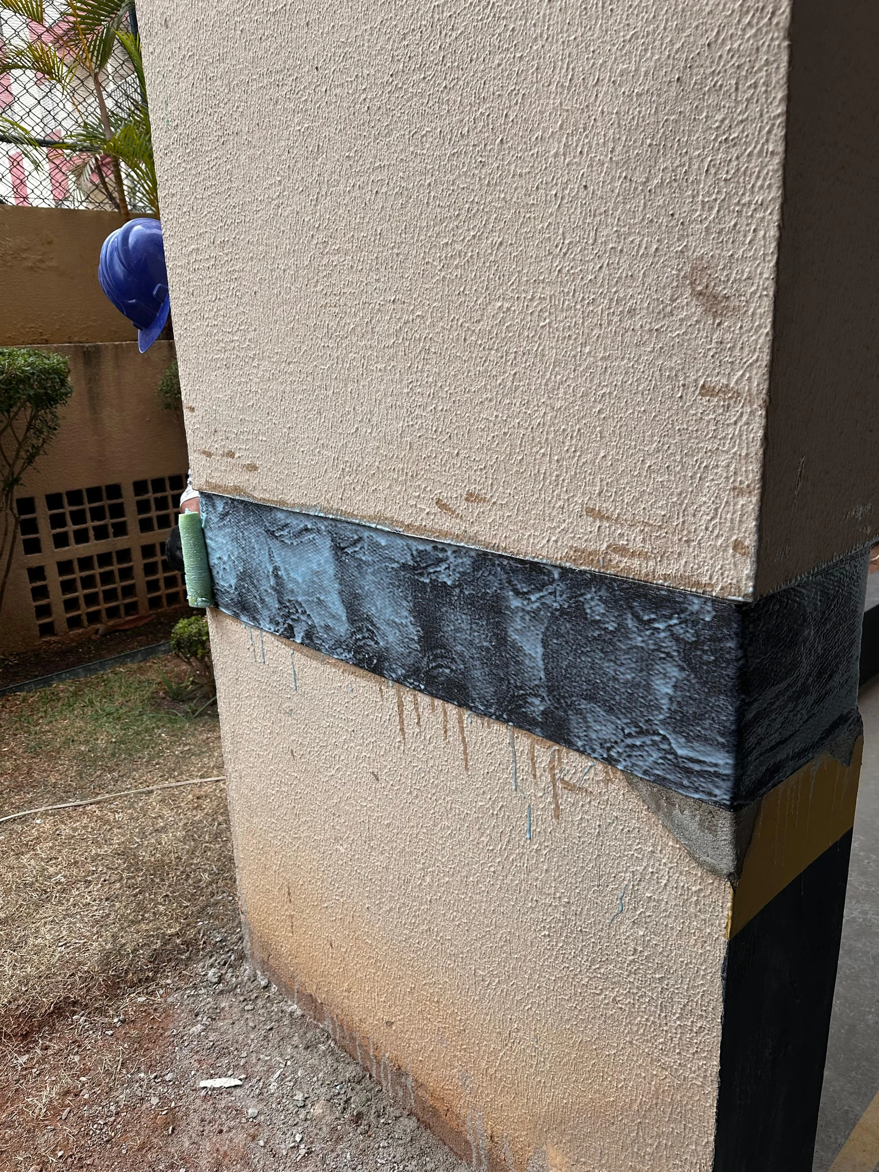 Aplicação de reforço com fibra de carbono ao redor de um pilar